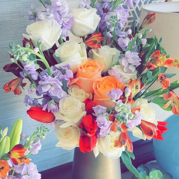Bouquet of cream, peach, red, and lavender flowers in a matte vase
