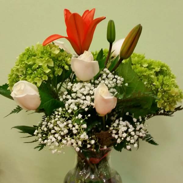 Bouquet of lilies, roses, hydrangeas, and baby's breath in a glass vase