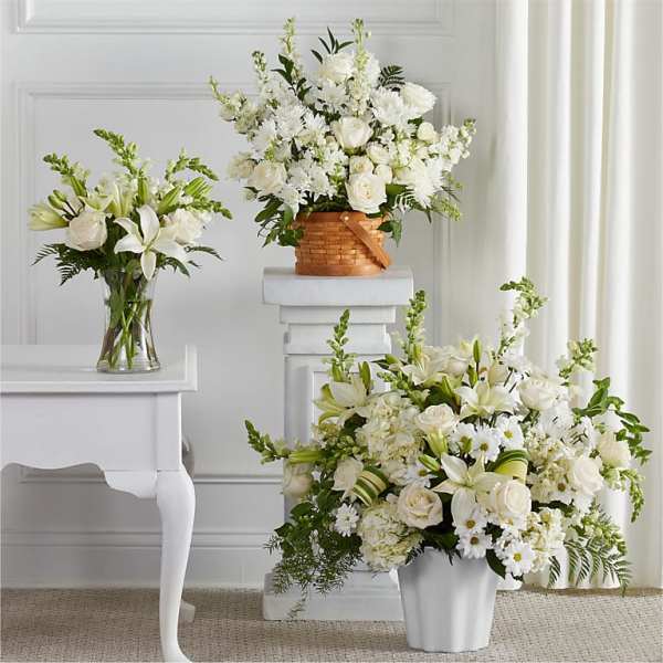 Three white floral arrangements in vases and a basket