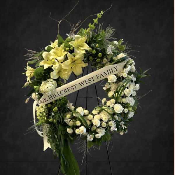Large floral wreath with yellow lilies and white flowers on a stand