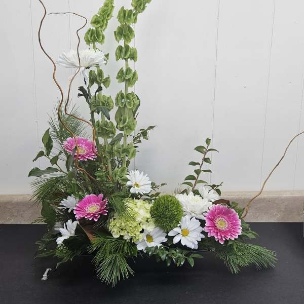 Low floral arrangement with pink gerberas, white daisies, and green blooms