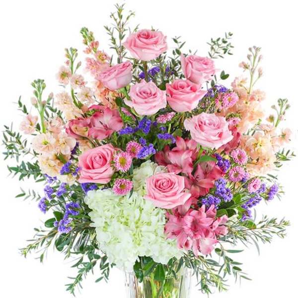 Pink roses and mixed flowers arranged in a clear glass vase