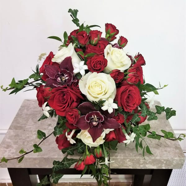 Red and white rose bouquet with dark orchids and ivy