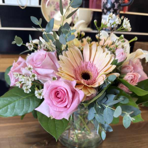 Pink roses and a peach gerbera daisy in a glass vase