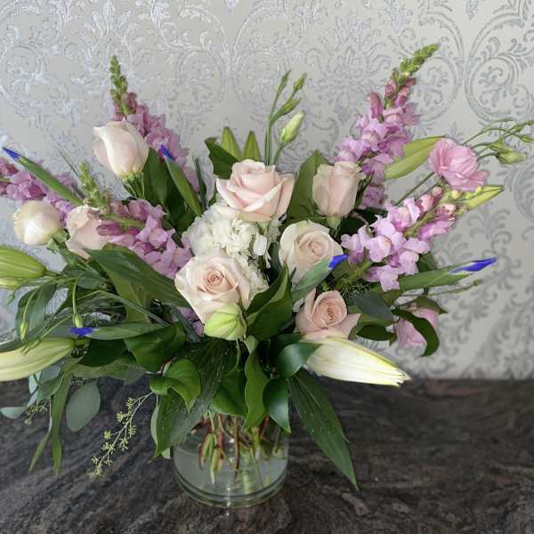 Pink roses and lilies arranged in a glass vase