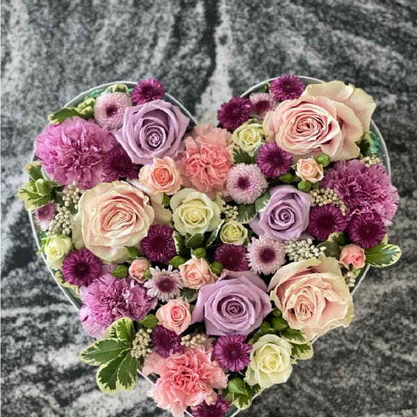 Heart-shaped floral arrangement with pink, lavender, and cream blooms