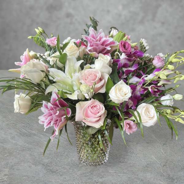 Pink and white mixed flower arrangement in a textured glass vase