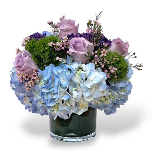 Lavender roses and blue hydrangeas in a glass vase