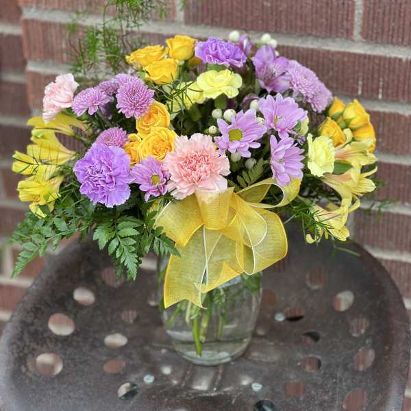 Colorful mixed bouquet in a clear glass vase with a yellow ribbon