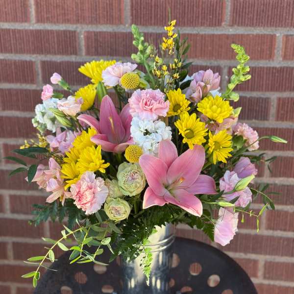 Pink lilies and yellow daisies in a metal vase
