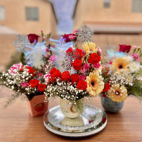 Three colorful flower arrangements in small vases on a table