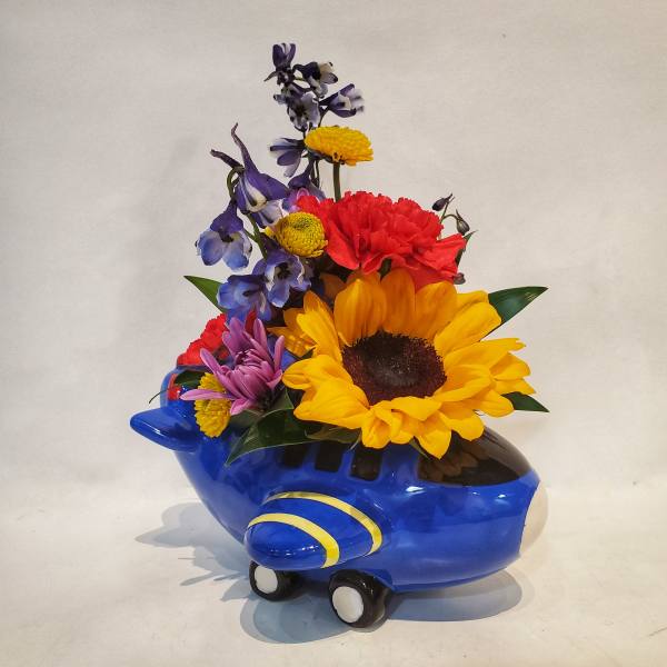 Colorful flowers arranged in a blue airplane-shaped container