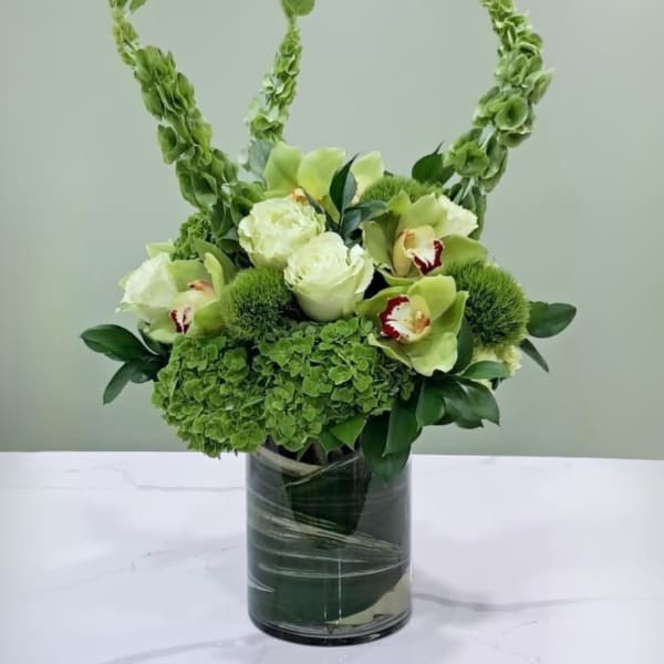 Green floral arrangement in a glass vase with tall arching stems