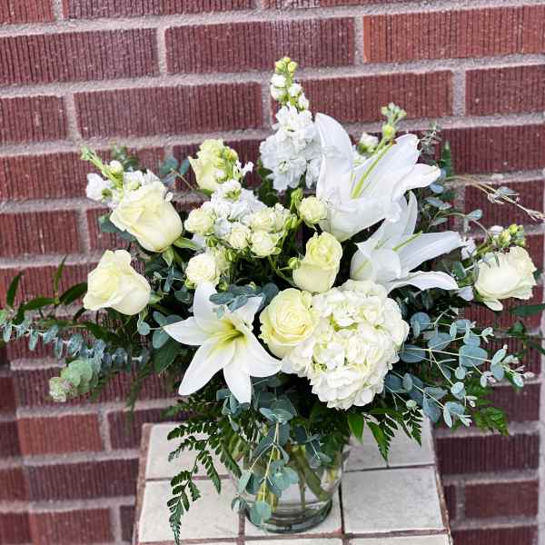 White roses and lilies arranged in a glass vase