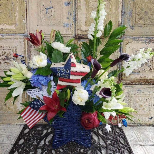 Patriotic floral arrangement in a star-shaped basket with an American flag