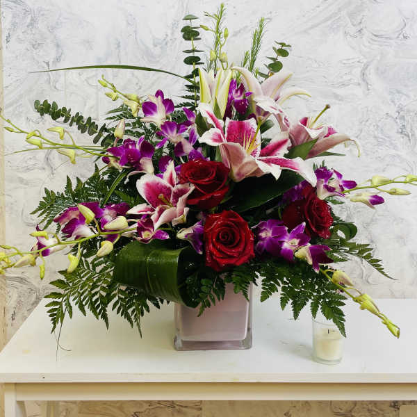 Bouquet of red roses and pink lilies in a square glass vase