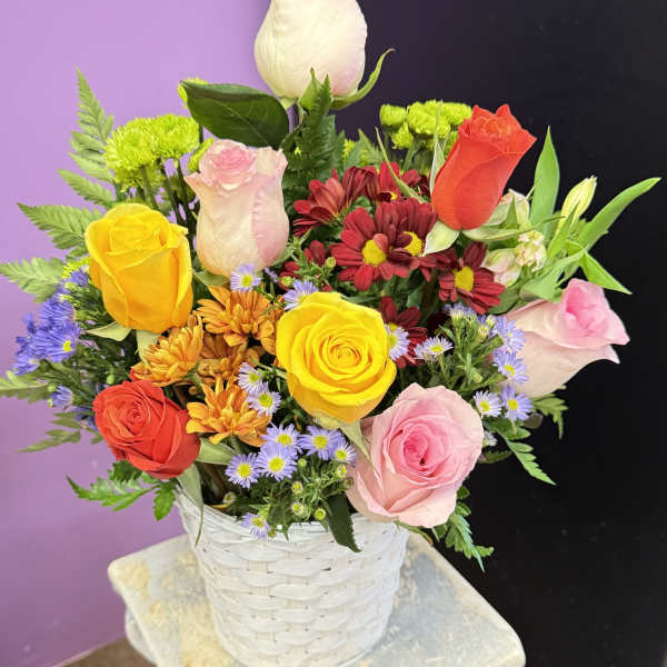Mixed bouquet of roses and daisies in a white basket