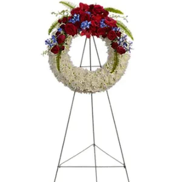 Standing funeral wreath with red and white flowers on a metal easel