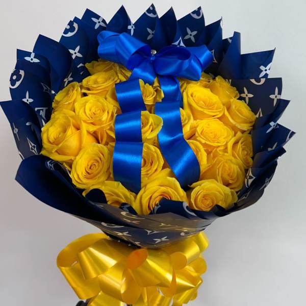 Bouquet of yellow roses wrapped in dark blue paper with a blue ribbon