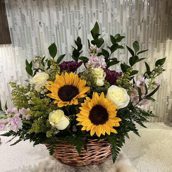 Basket arrangement with sunflowers, white roses, and purple blooms