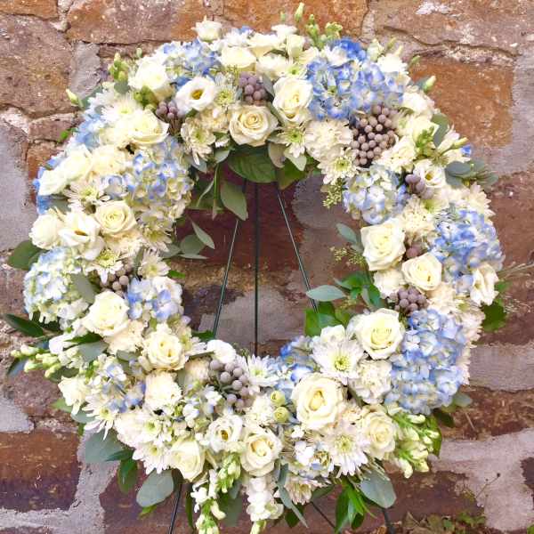 Circular wreath of white and blue flowers on a stand