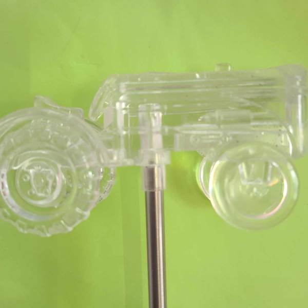 Clear plastic toy car mounted on a metal rod against a green background