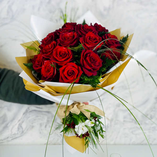 Bouquet of red roses wrapped in white and gold paper