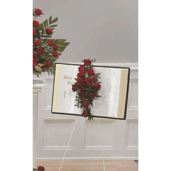 Red rose floral spray on an open Bible on an easel
