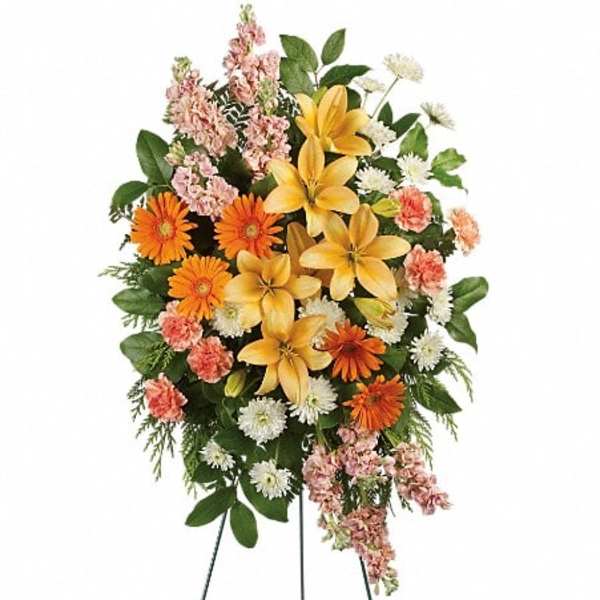 Standing floral spray with yellow lilies, orange daisies, and pink flowers