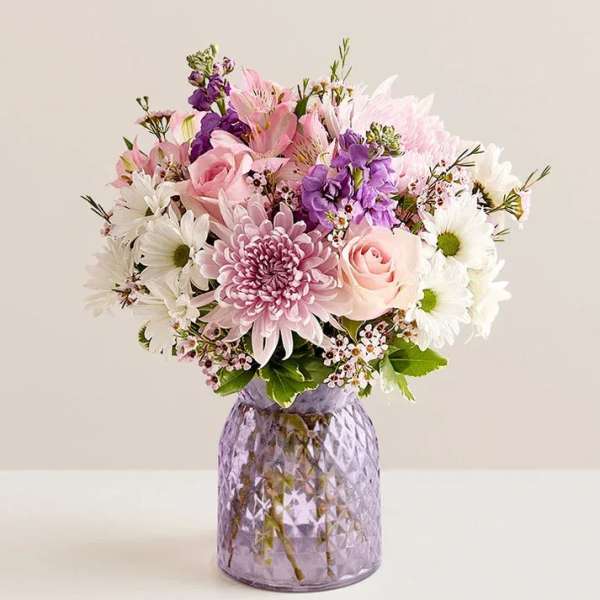 Pink and white mixed bouquet in a purple glass vase