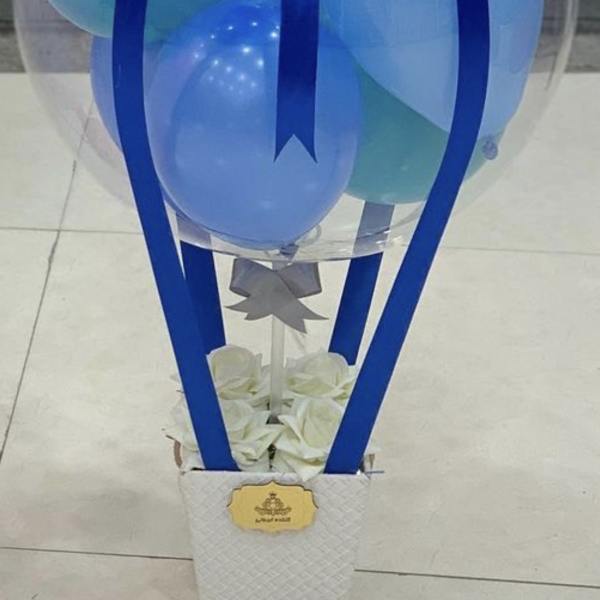 Clear balloon dome with blue balloons and ribbon on a white box