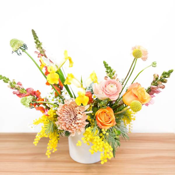 Mixed bouquet in a white vase with orange, pink, and yellow flowers