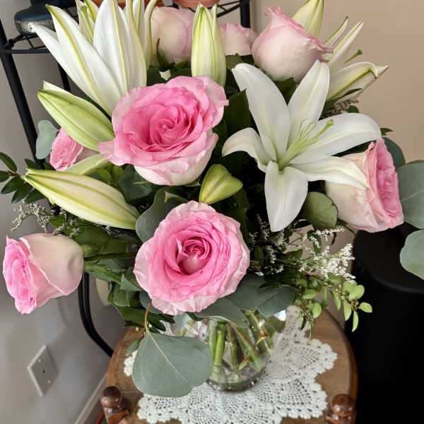 Pink roses and white lilies arranged in a clear glass vase