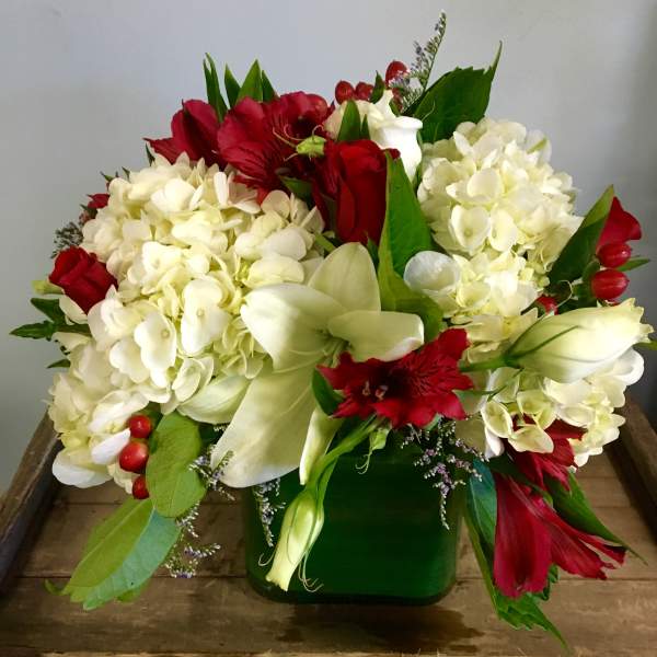 Red and white floral arrangement in a green vase