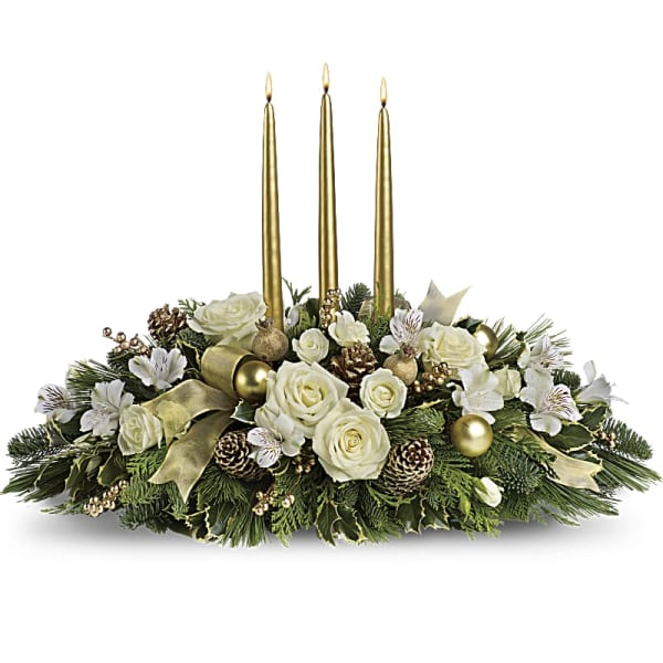 White roses and greenery arranged with three gold candles
