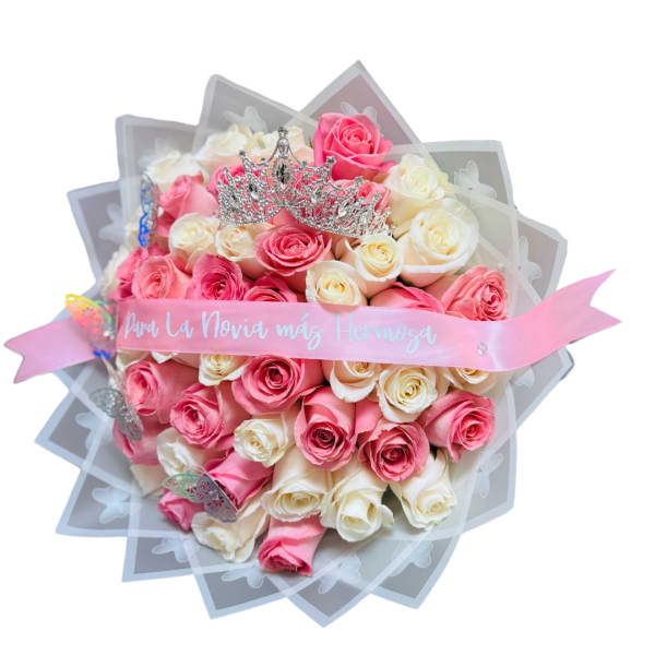 Round bouquet of pink and cream roses topped with a silver tiara and pink printed ribbon.