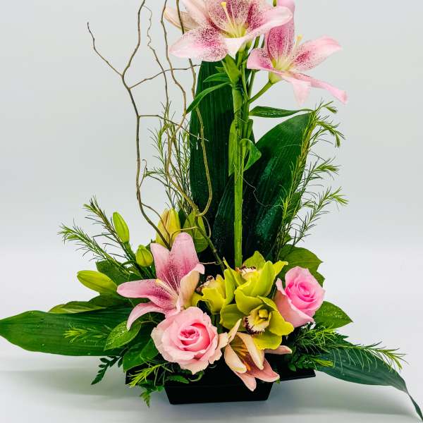 Pink lilies and roses arranged in a black rectangular vase