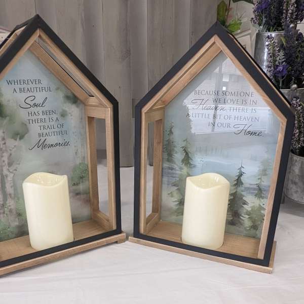 Two house-shaped memorial lanterns with candles and printed sympathy messages