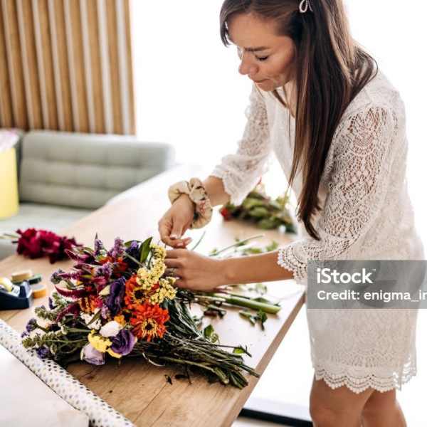 Woman arranging a colorful bouquet on a table