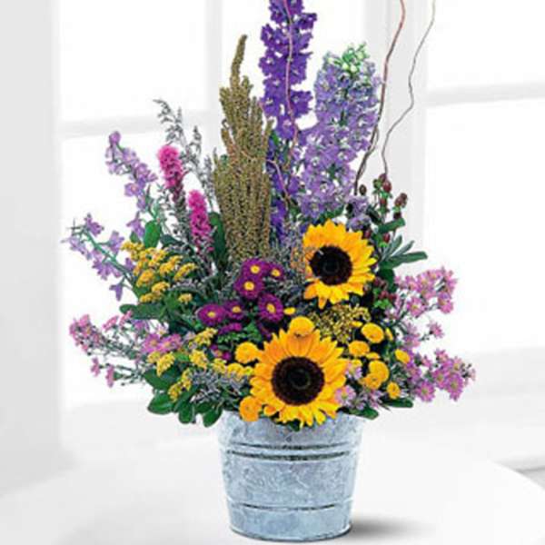 Mixed bouquet with sunflowers and purple flowers in a metal bucket