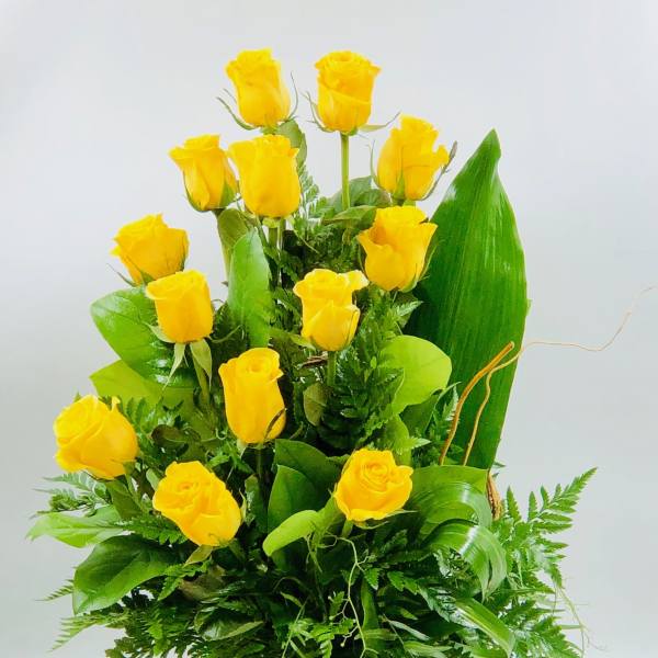 Yellow roses arranged in a woven basket with lush greenery
