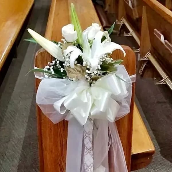 White lily bouquet with a large satin bow on a church pew
