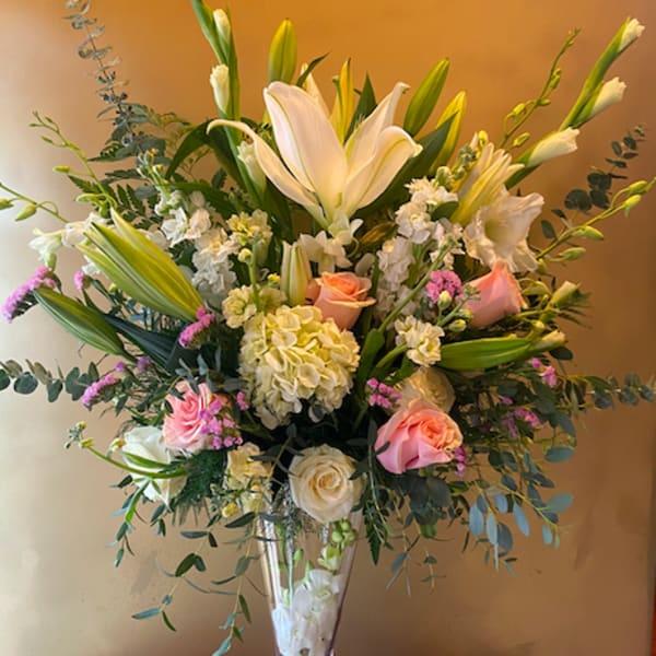 Tall bouquet of white lilies and pink roses in a clear glass vase