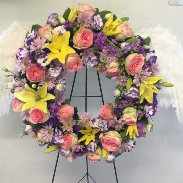 Floral wreath with pink and purple flowers and white feather wings