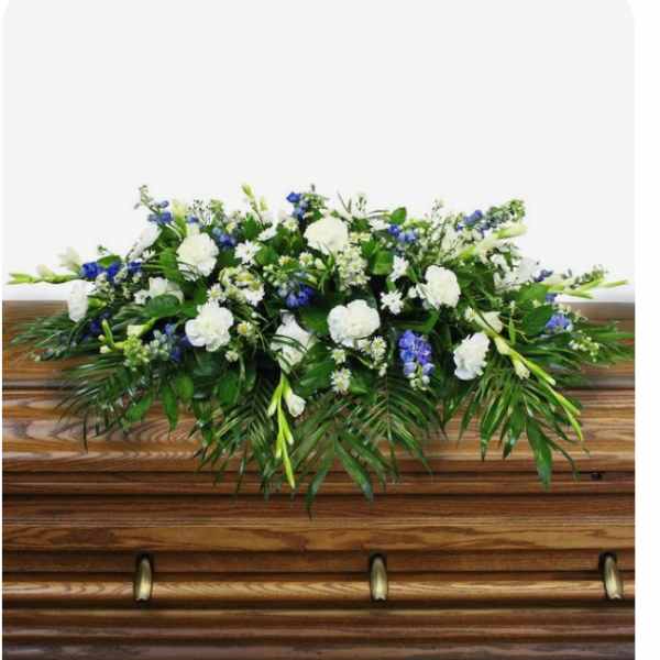 White and blue floral spray on a wooden casket