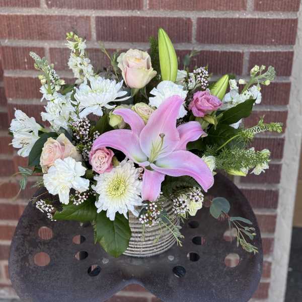 Pink lily and pale roses arranged in a striped vase