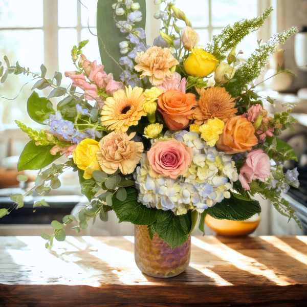 Mixed pastel flower arrangement in a glass vase