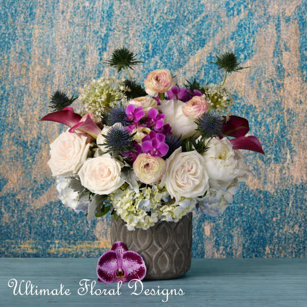 Mixed bouquet of white, pink, and purple flowers in a gray vase
