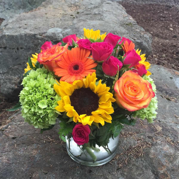 Bouquet of sunflowers, roses, gerbera daisies, and green hydrangeas in a silver vase