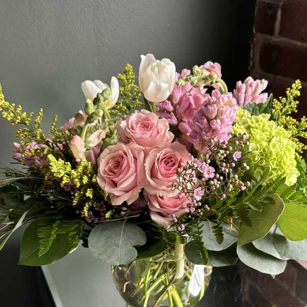 Pink roses and white tulips in a clear glass vase